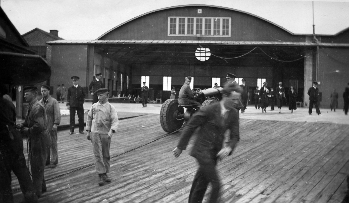 En traktor drar upp Charles Lindberghs flygplan på en slip vid dennes besök på F 2 Karlskrona flygstation på Stumholmen i september 1933. Folksamling i rörelse.