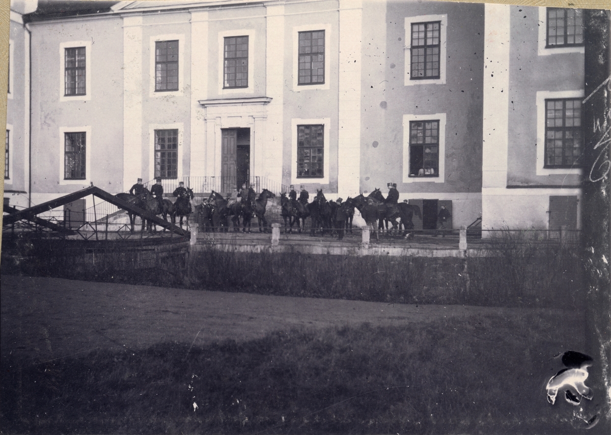 Soldater till häst framför en byggnad.