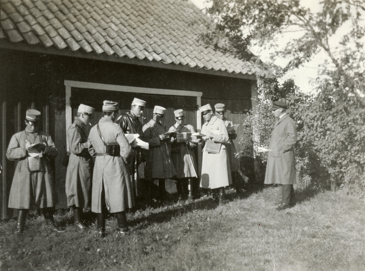 Text i fotoalbum: "Förbindelsekursen 1920". Soldater studerar kartor framför en byggnad.