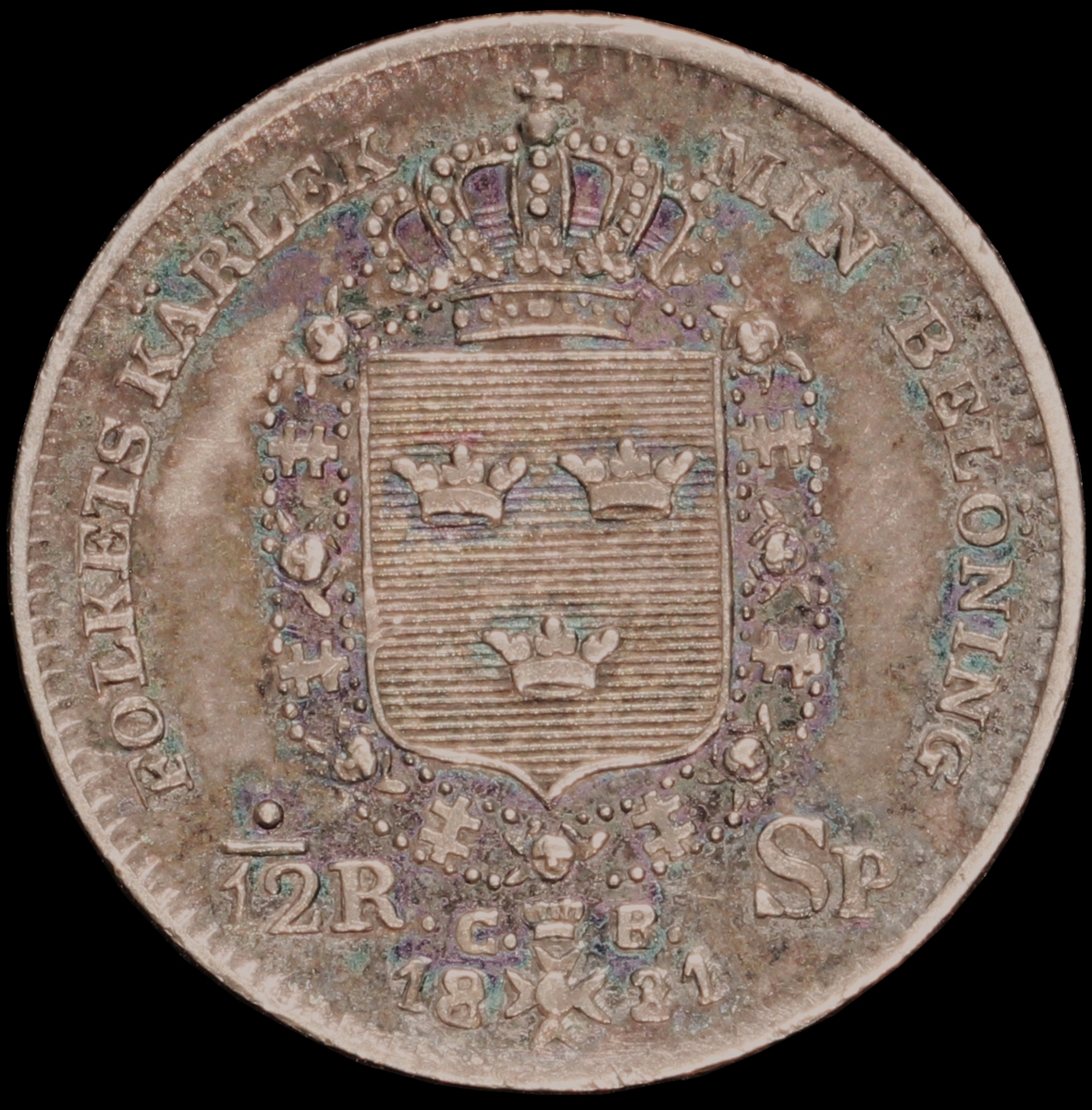 Mynt med valören 1/12 riksdaler specie. Åtsidan har en bild av Kung Karl XIV Johan och frånsidan visar lilla riksvapnet, valör samt kungens valspråk "Folkets kärlek min belöning".