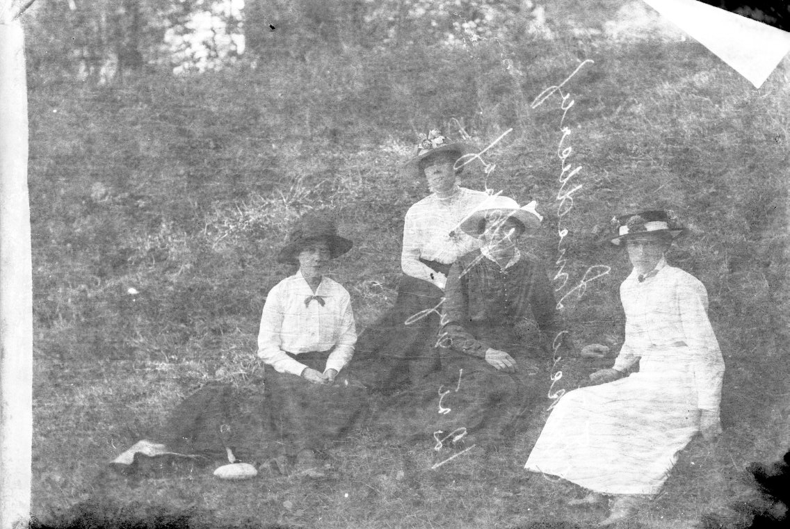 Fyra kvinnor sitter på en grässlänt, troligen i närheten av Visingsborgs slottsruin. Det är sommar.