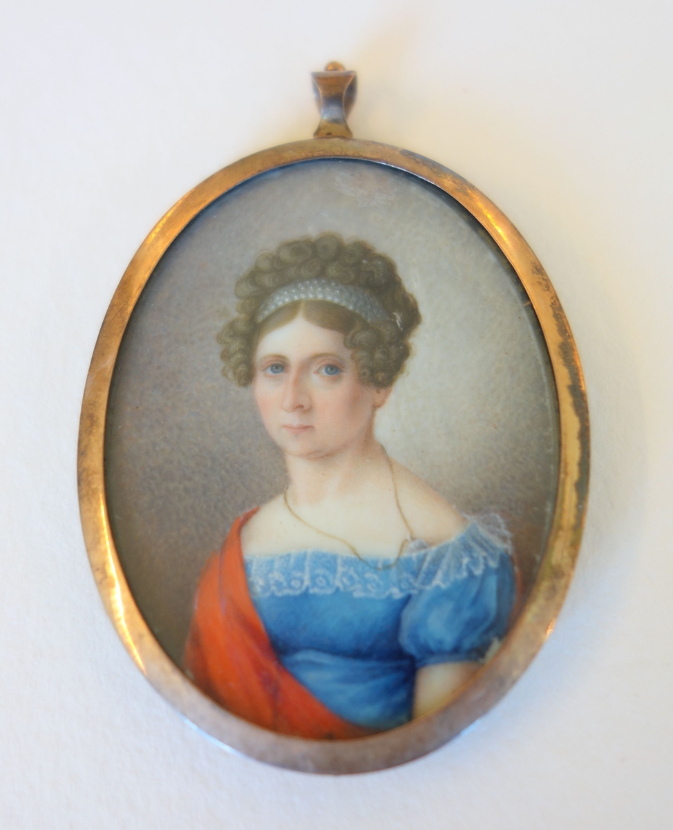 Oval medaljong med gullramme. Avers, håndmalt portrett av ung kvinne i blå empirekjole. Revers, flettet mørk blondt hår.