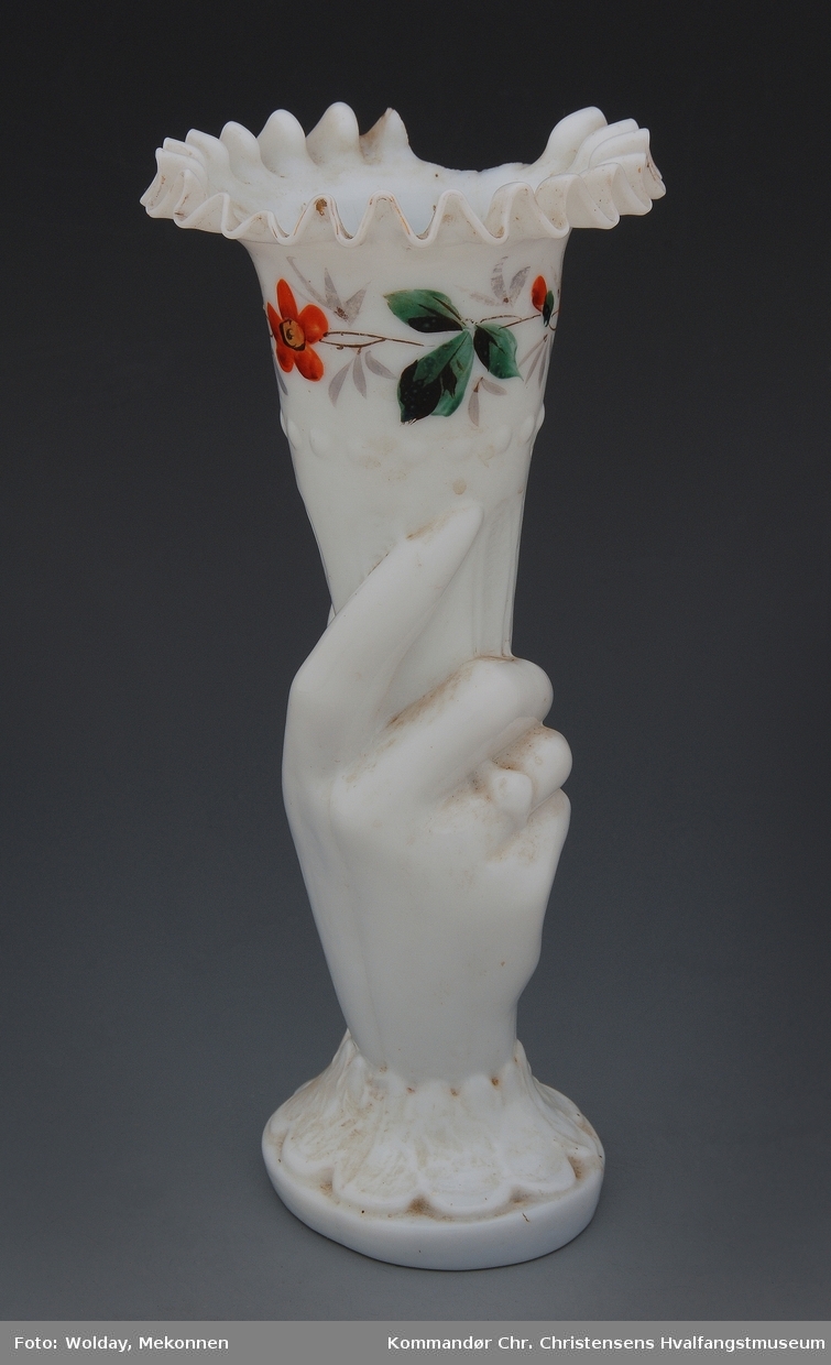 Formet som hånd som holder et horn, dekorert med blomsterranke.