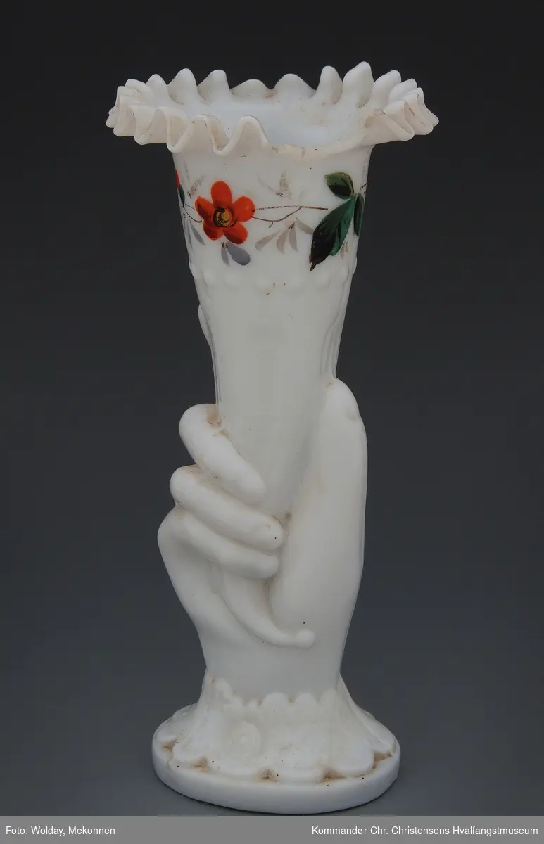Formet som hånd som holder et horn, dekorert med blomsterranke.