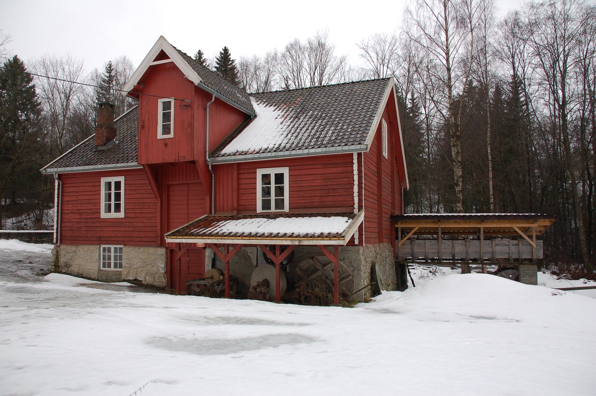 Tømmerbygning i tre etasjer. Rødmalt med teglstenstak. Rekonstruert vasshjul, renne og flishøvel.
