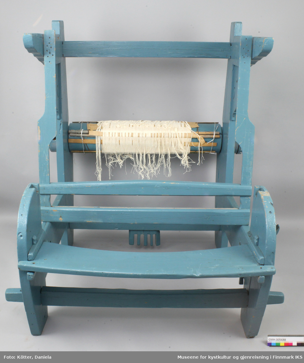Vevstolen er bygd av tre og overflaten er overtrukket med blå lakk. Delene har slagmerker ved sammenføyningene til enklere montering. Vevstolen fremstår som fragmentarisk. Oppheng til skjeslaget, brystbom, stoffbom og mange andre vesentlige deler mangler. På garnbommen er det sveipet på renningen og spiler. Det er mulig at denne vevstolen var supplert med deler registrert som GMH.005690.