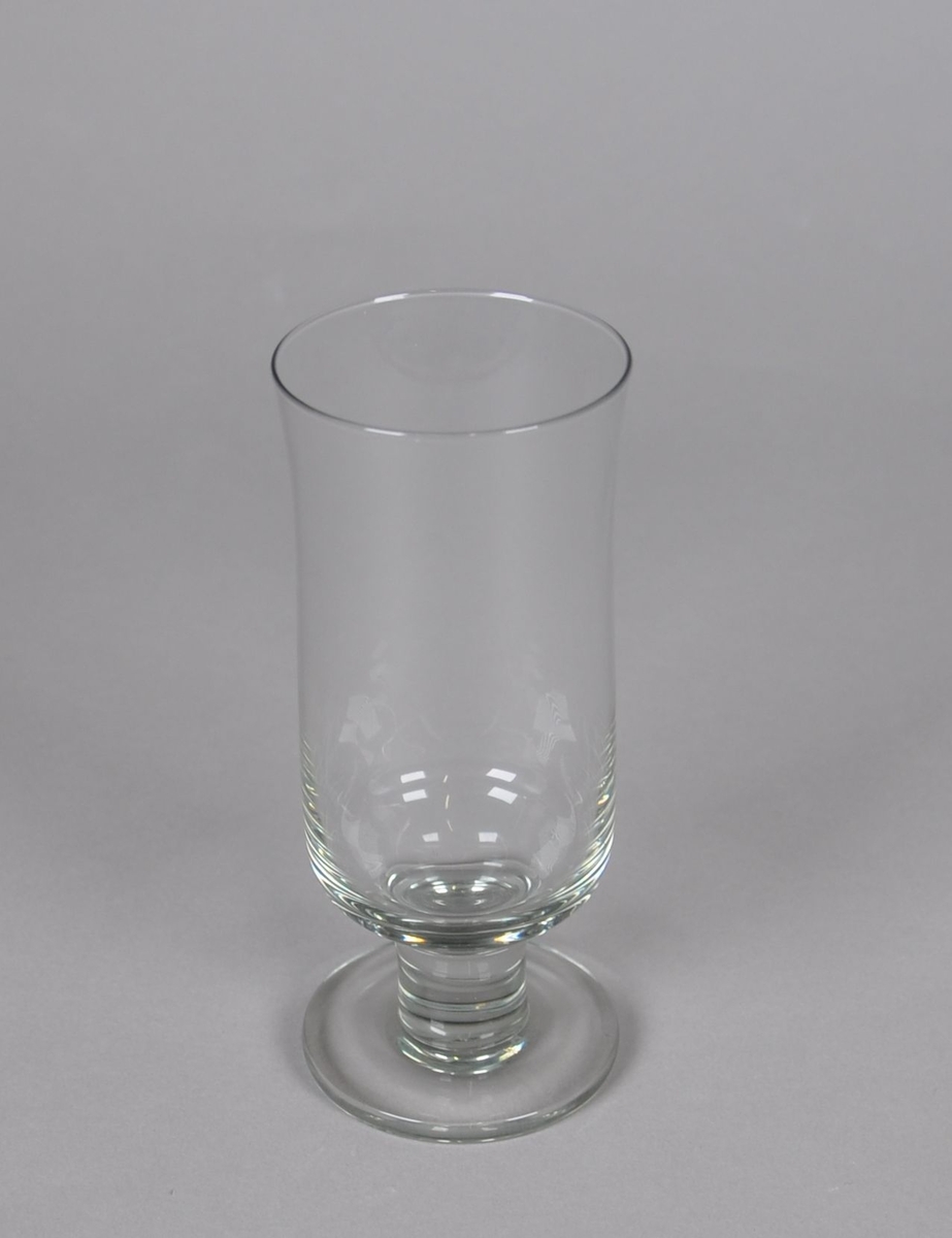 Grått hvitvinsglass. Glasset står på sylindrisk stett og rund sokkel. Glasset er sylindrisk, med svak konkav kurve under drikkeranden.
