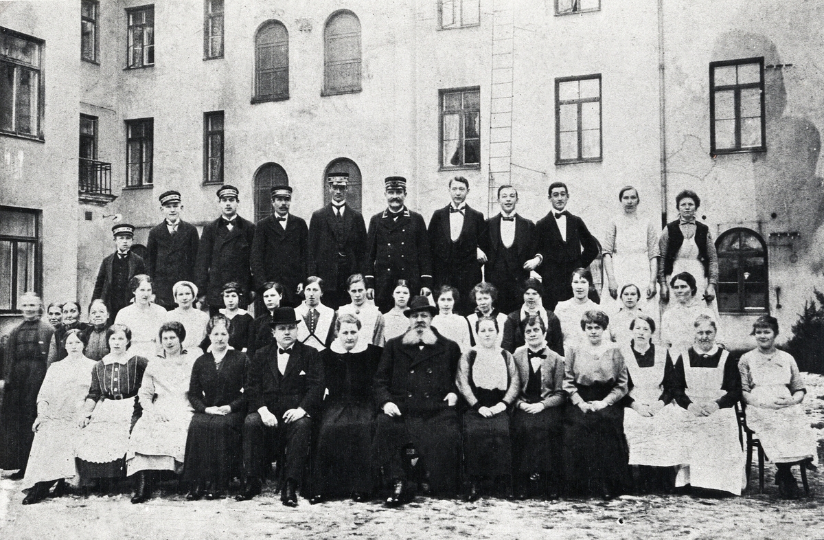 Källarmästare Axel Gustafson vid Växjö Stadshotell med fru och personal på hotellets innergård. 1918.