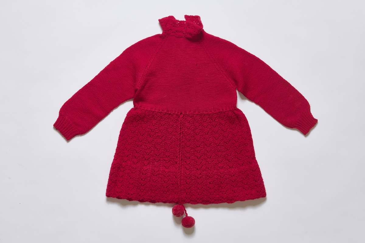 Kjole strikket i rødt ullgarn. Overdelen er glattstrikket, mens skjørtet er en form for kunststrikk. Kjolen har bred fald nederst, og har muligens vært justert etter barnets høyde. 