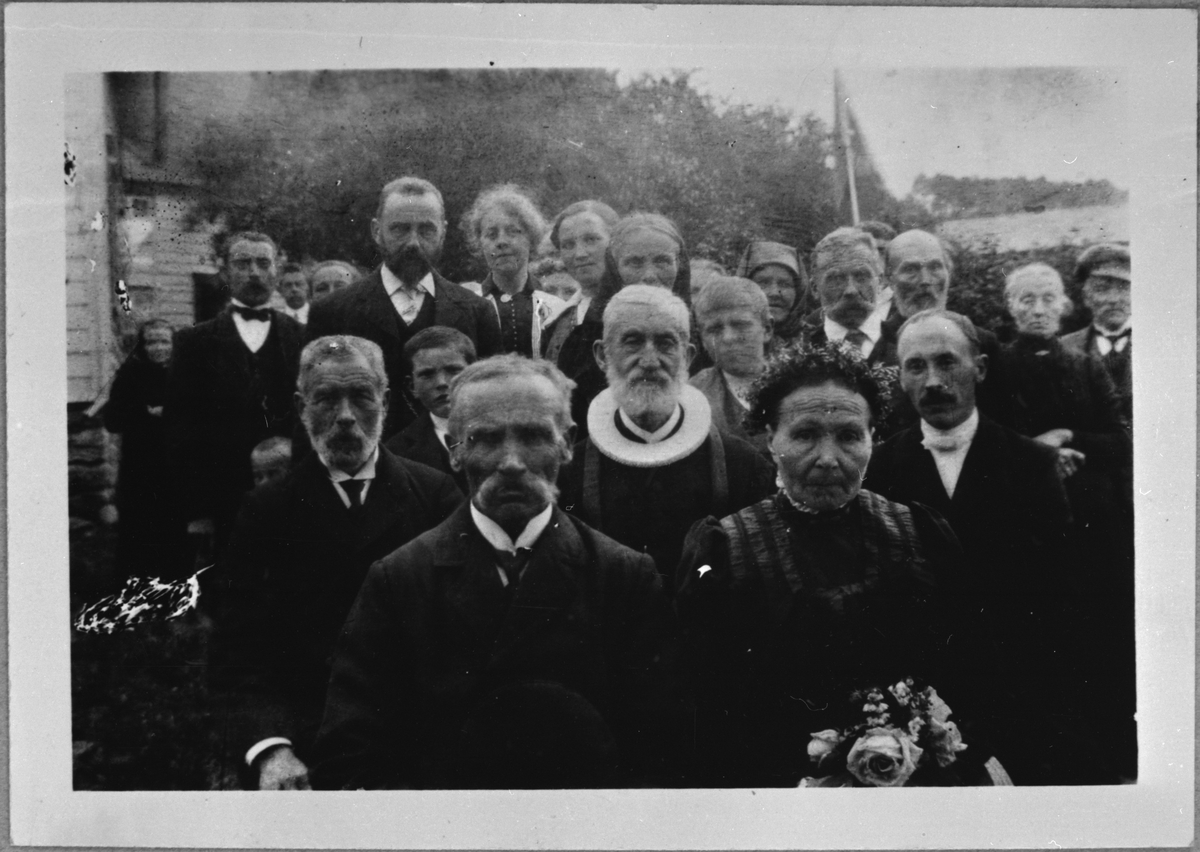 Bryllaupslaget til kyrkjetenar Kolbein Haugland og Inger Kristine Skjold i Ølen, 26. juli 1915. Presten de Seuv og klokkaren E. Einarsen sit bak brudeparet.