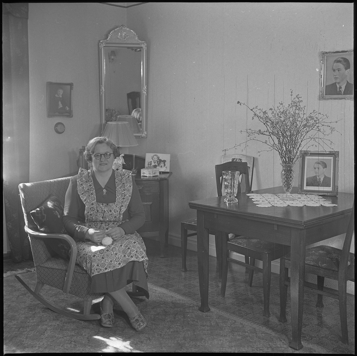 Hilda Andersson i sitt hem, troligen Hemvägen 34. På väggen och på bordet syns porträtt av sonen Lars Pettersson. . 19 mars 1950