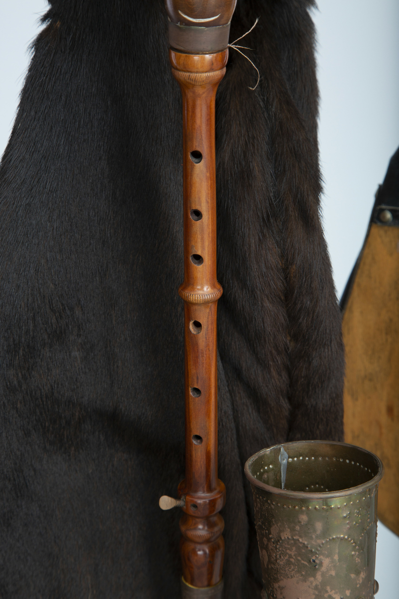 Instrument med sekk av hundeskinn, korthåret, mørk brun pels. Blåsebelg, en bordun og en melodipipe. Melodipipens øvre ende stikker ut av et skåret, stilisert bukkehode av tre med messingdekor. 6+1 fingerhull. Begge pipene har sylindrisk boring og ender i oppoverbøyde horn forsynt med hamrede messingplater. Bordunpipen består av fire dreide ledd (+horn) med messingknapper og ornamenter.