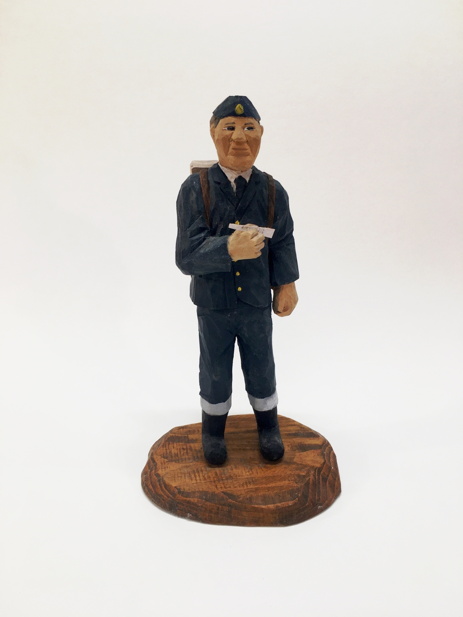 Figurin förställande en brevbärare med uniform, ryggsäck och mössa. Brevbäraren har ett brev i handen.