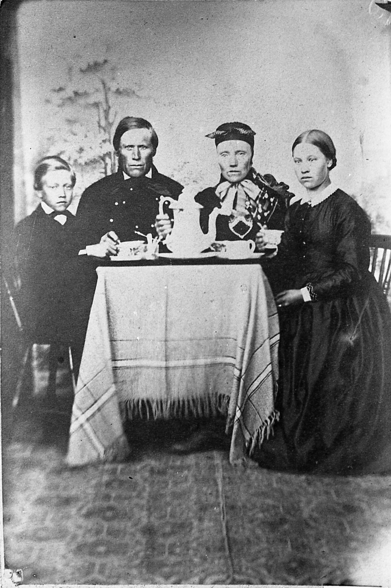 Familieportrett. Halvor og Turid Kvisle med barn. Foreldrene er kledd i "fjellkler", barna i bymote. Antagelig fotografert omkring 1860.