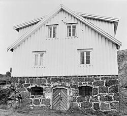 Hvit bolig i fiskeværet Nusfjord. Kortveggen imot. Kjellermu