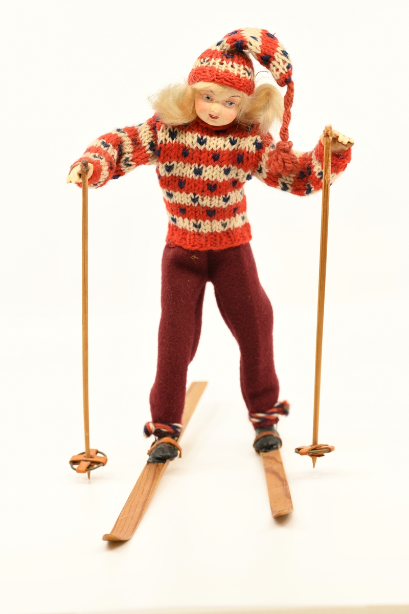 Dukke som forestiller jente med ski på beina