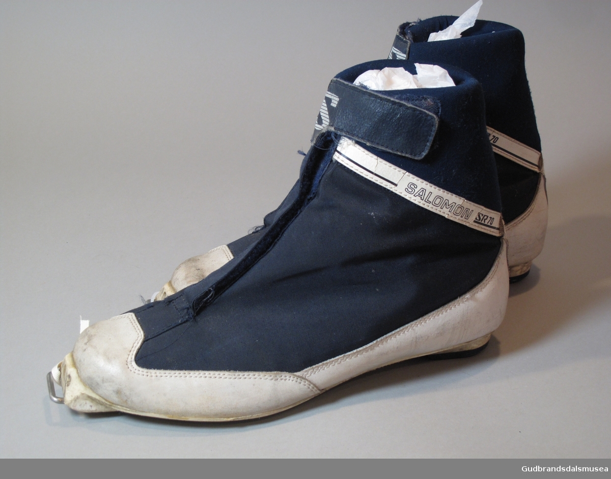 1 par blå Salomon SR70, Cross Country Ski Shoes. Lukning med borrelås over skolisser. Skoen er i syntetisk, vannavstøtende materiale, forsterket med lær på snuter og hæler. Såler i plast.