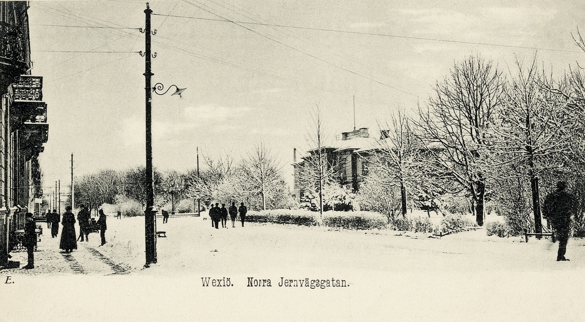 Norra Järnvägsgatan, Växjö, med vy österut fr. Klostergatans mynning. Tidigt 1900-tal.
Till vänster skymtar hörnhuset i kv. Linné, till höger syns järnvägsstationen.
