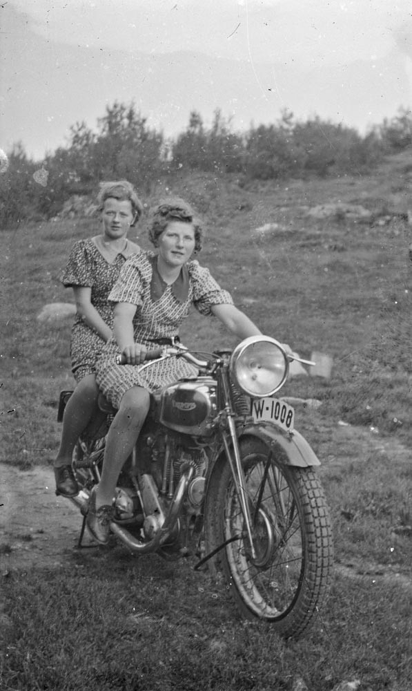 Leirfjord. To unge jenter på motorsykkel.
Foran: Vigdis Edvardsen (f. Benjaminsen), bak: Hjørdis Olsen (f. Benjaminsen).
Bildet er brukt i Leirfjordkalenderen - august 2022