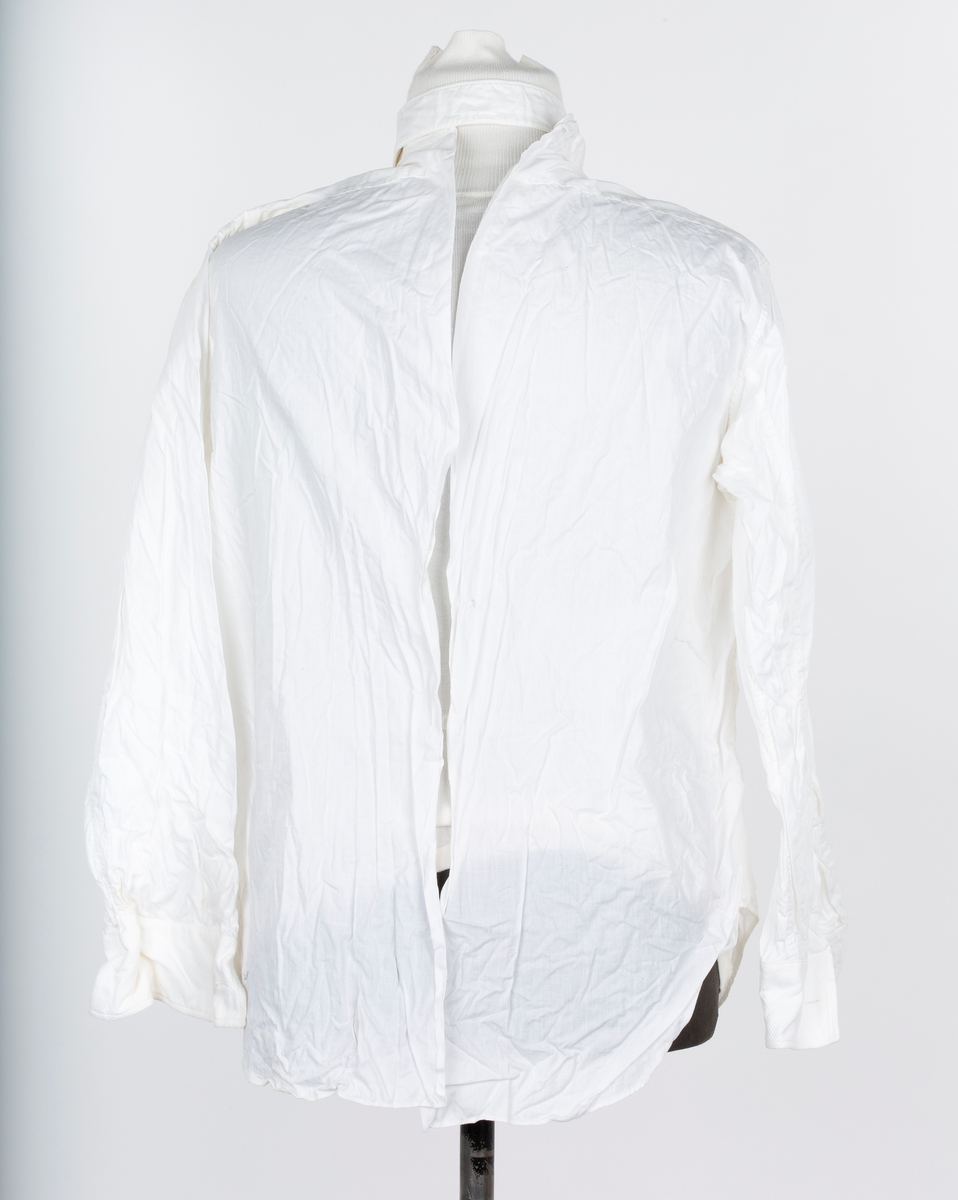 Skjorte. Smoking- eller Gallaskjorte, herre, Hvit bomull, bak-kneppet med stivt skjortebryst, halslinning  og løs snipp. Mrk: Golf de Luxe.