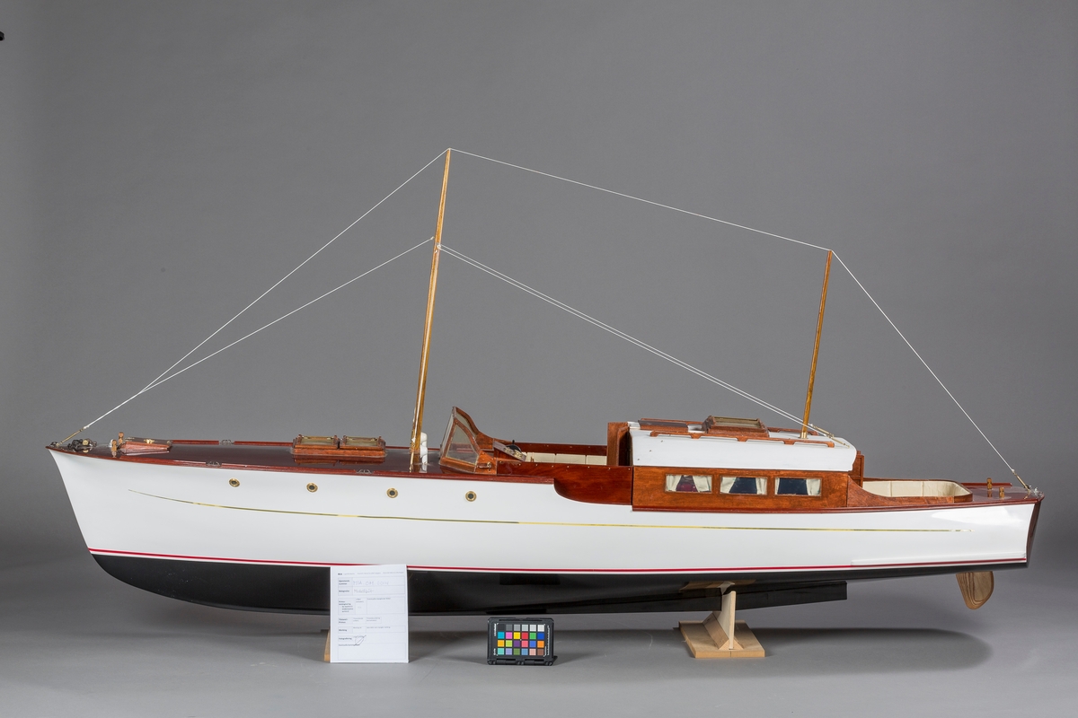 Modell av motorkrysseren "Bello". En Furuholmenkontruksjon. Kahytt med salong, og åpen styrekonstruksjon. To enkle master. Ikke originale båtstøtter, laget av museet ved inntak.