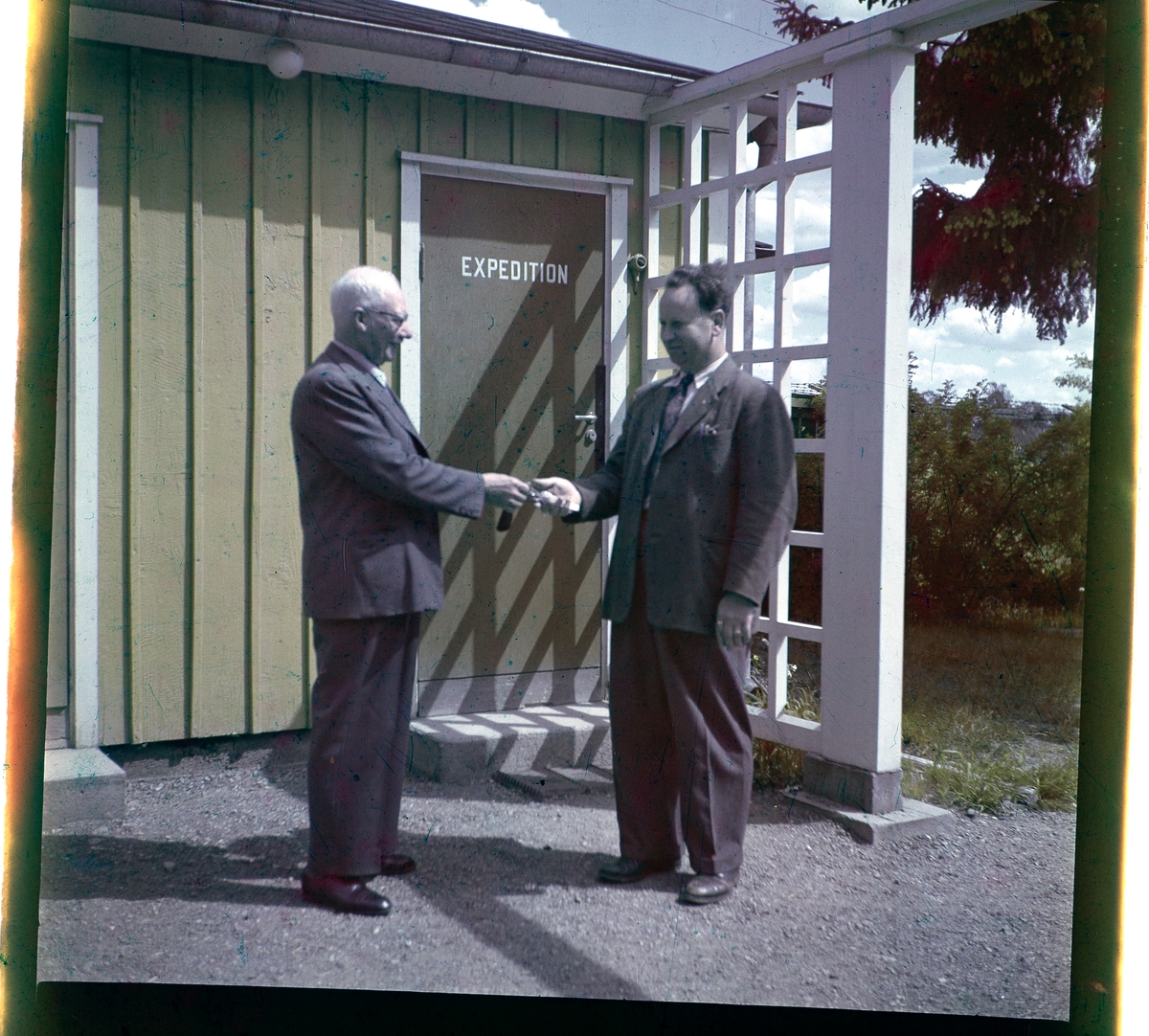 Negativ på två män utanför en byggnad i Folkets Park i Linköping. Personerna är Herman E. Nilsson och Alvar Vincent.
