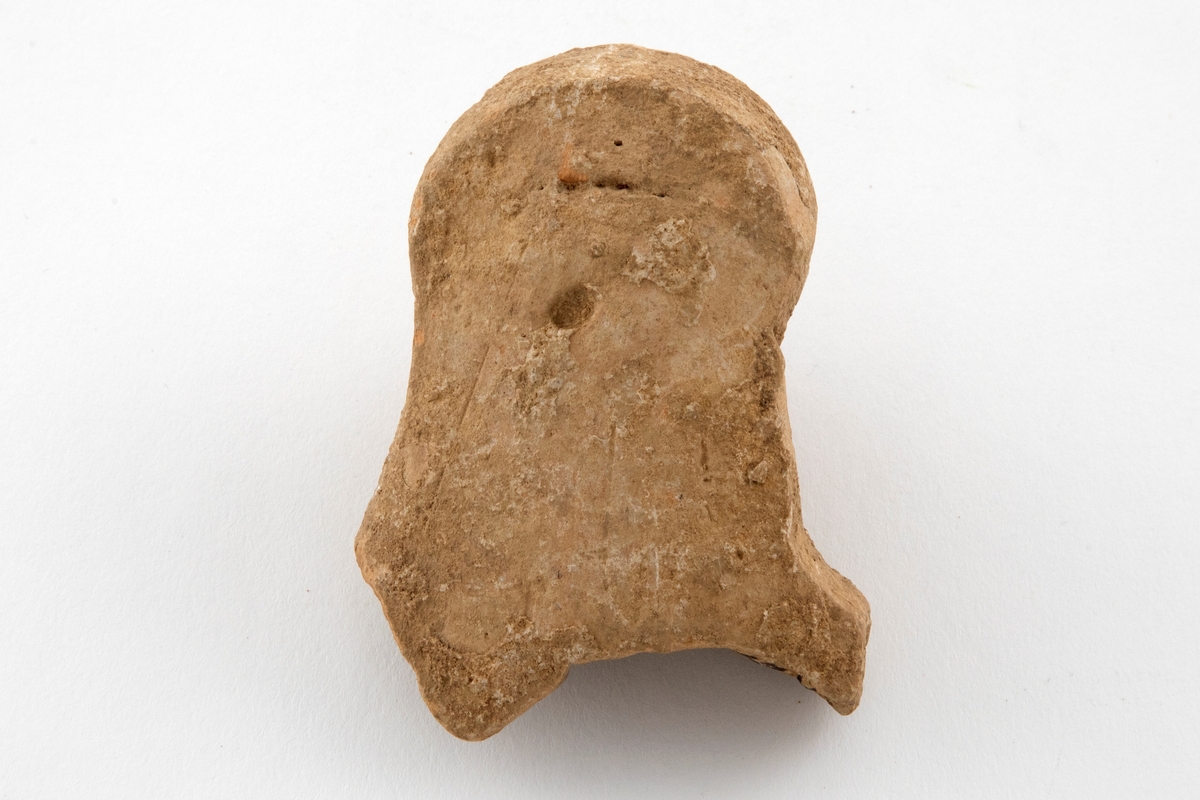 Fragment av figurin, utformet som et hult kvinnehode i terrakotta. Grågult gods.