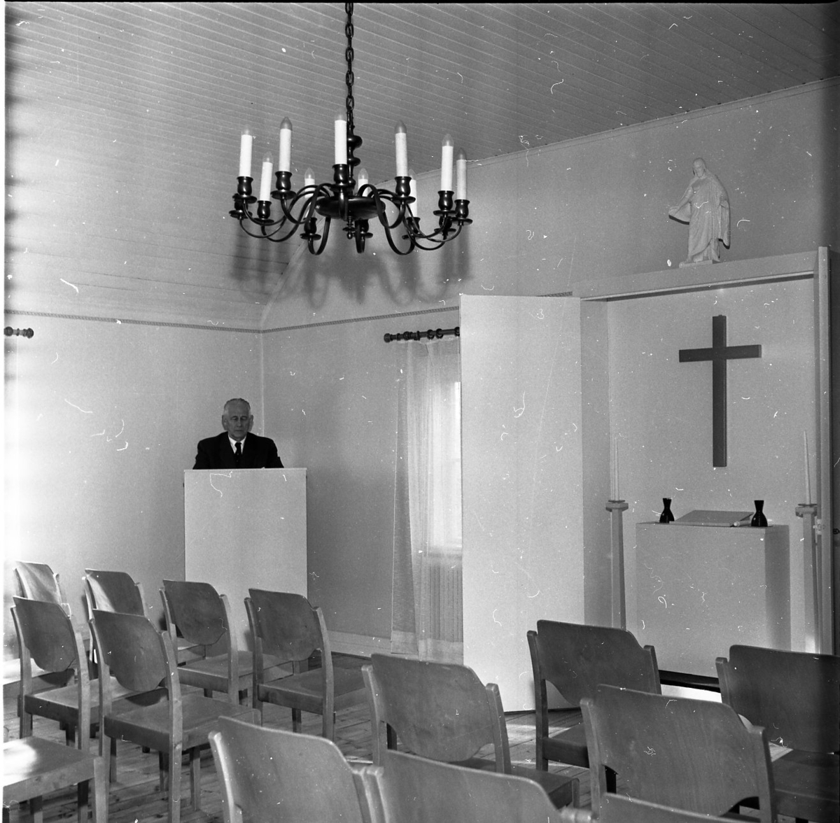 En herre står i en talarstol bredvid ett altare.
