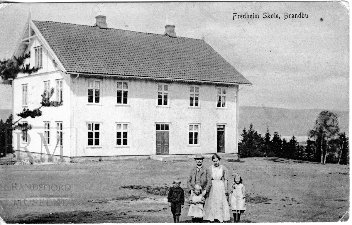 Fredheim skole i Tingelstad. En skolebygning, læreren med familie i forgrunnen.