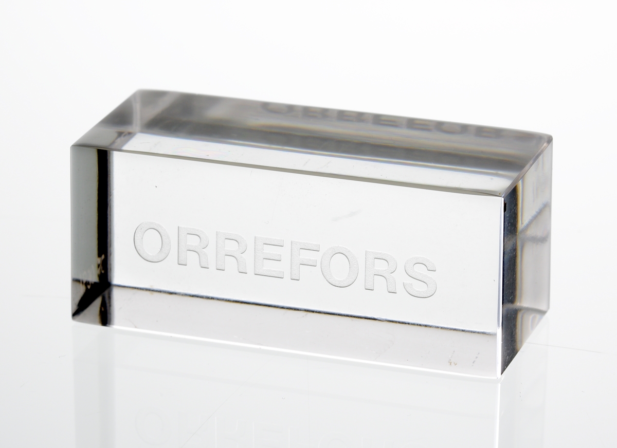 Design: Ingeborg Lundin.
Glasblock, rätblocksform med graverad text: "ORREFORS".