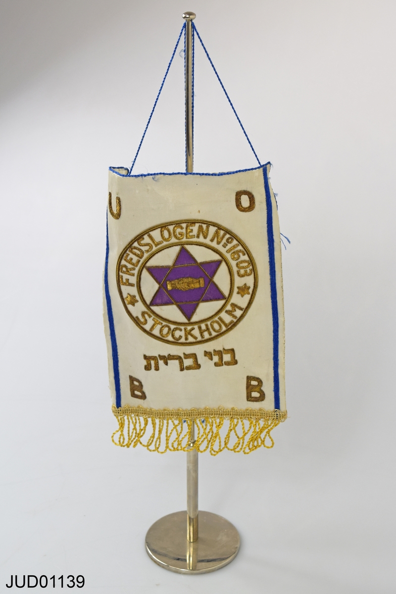 Vit bordsflagga på stång med text fredslogen 1603, BB, UO. Från organisationen Bnei Brith.