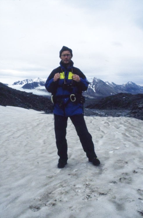En man med mindre ryggsäck står på ett snöklätt
berg, Dronning Mauds fjell. Han bär Svenska Polarforskningssekretariatets klädsel.
