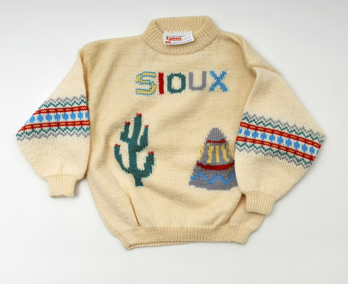 Strikket genser, med fargerikt mønster på ermene, på brystet teskt "SIOUX" og nede avbidning av  en kaktus og en tipi, ribbestrikk rundt halsen, nederst på bolen og ermene og fargerikt mønster på ermene, str. 2 år