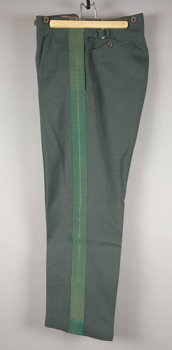 Grønn uniformsbukse av ull (gabardin) med grønn stripe på yttersiden av hvert ben. Knapper i gylfen og innsydde lommer.