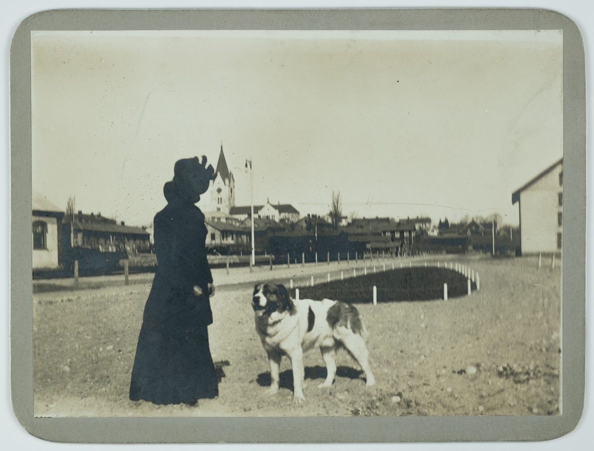 En kvinna med en hund, "Baron". Nora kyrka i bakgrunden. 
Fotot taget i maj 1901.