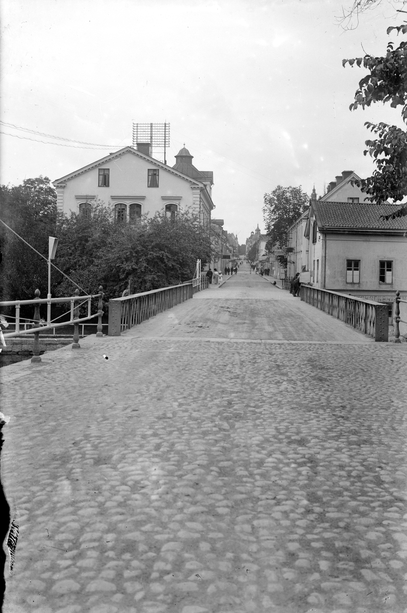 Vy längs med Storgatan i Linköping. Den okända fotografen hade placerat sig invid Stångebro och riktat sin kamera rakt västerut. Tiden var omkring 1920. Hitom Storgatans skärning med Hamngatan ser vi till vänster delar av fattigvårdens anläggning i staden. Till höger ses södra delen av en lång byggnad som inrymde Stångebro tvättinrättning.