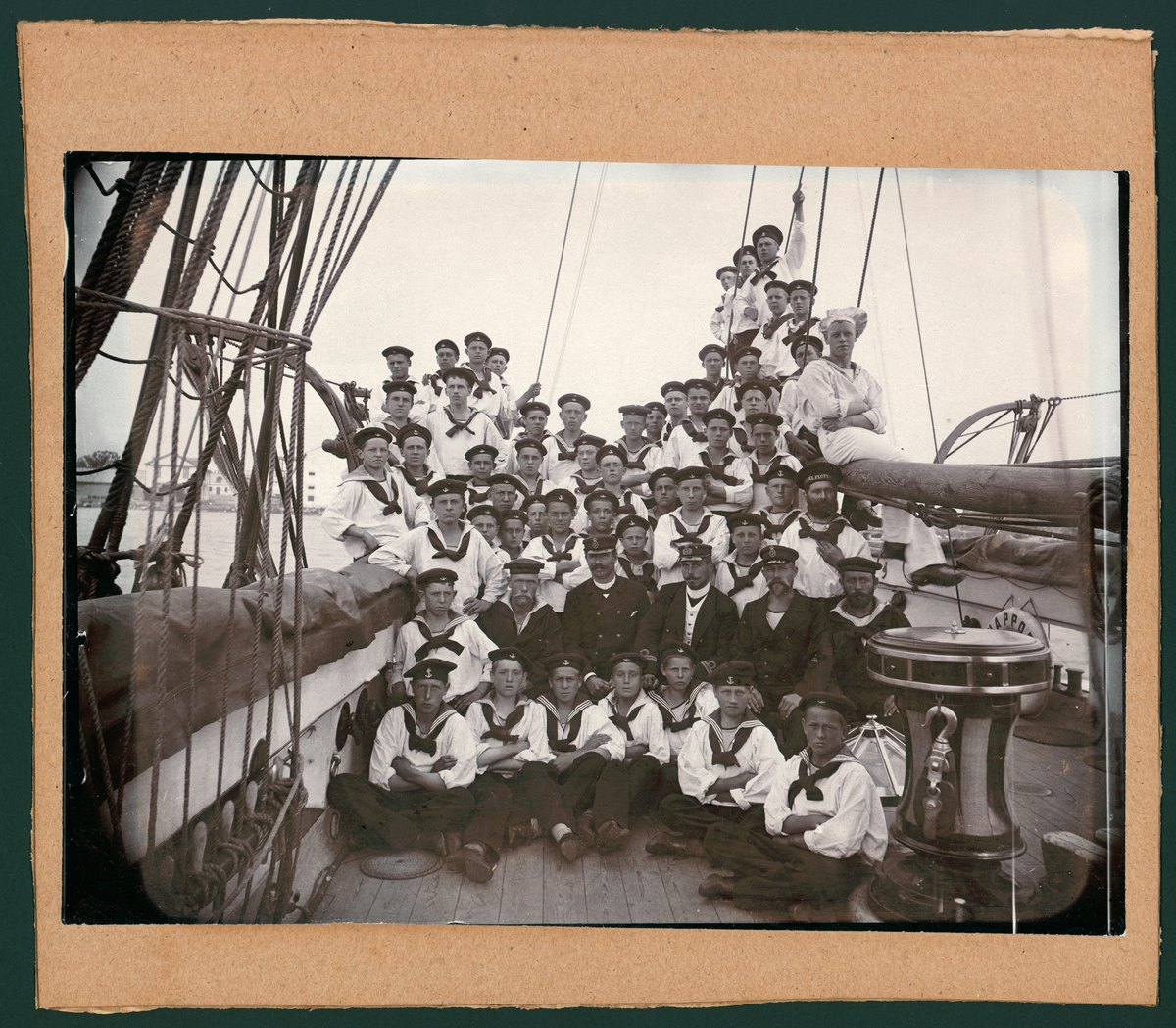 Bilden visar skeppsgossar och befäl ombord på skeppsgossbriggen Snappopp som har samlats på förskeppet för en gruppfoto.