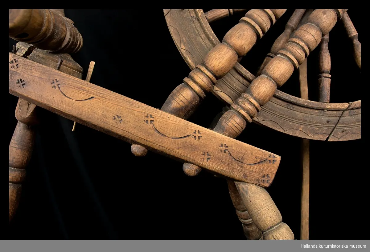 Spinnrock av trä med axlar av järn och lager för rullen av läder. Snedställt bröst. Hjulet vilar på dubbla stöd. Stjärnliknande ornament samt bågar inbrända på bröst och hjul. Märkt enligt avritad text.