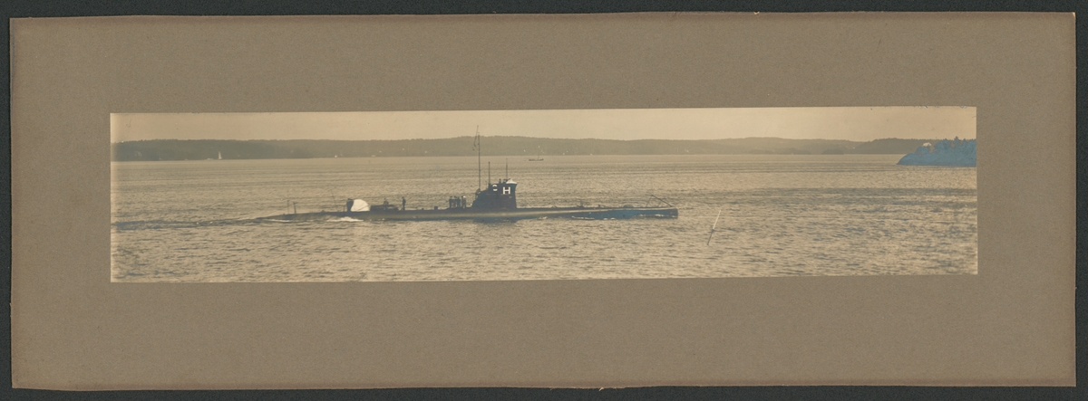 Bilden föreställer ubåten Hajen till sjöss. Båten gör låg fart. På däck står en grupp besättningsmän i samtal medan andra håller på med olika arbeten.