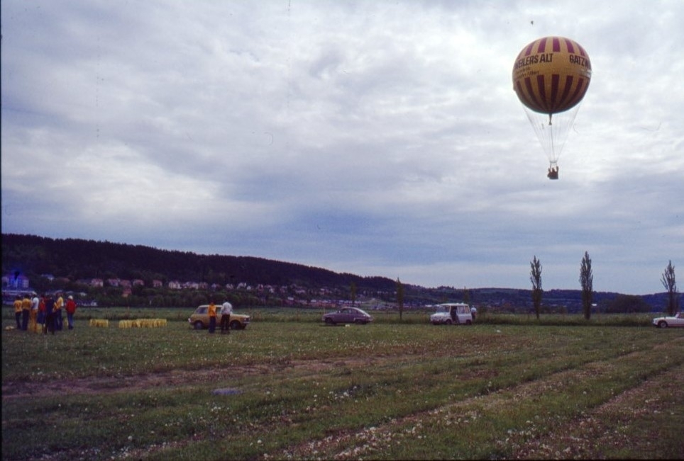 En västtysk vätgasballong märkt "Gatzweilers Alt" i luften ovanför gräsplanen mellan Gränna stad och Vättern. Ballongens pilot är möjligen Jojo Maes.