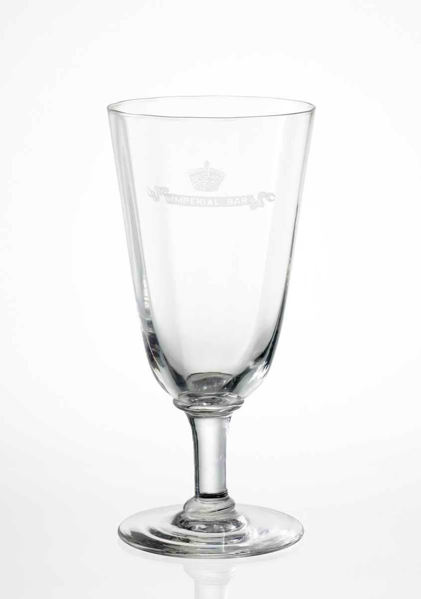 Design: Okänd. 
Ölglas på ben och fot. Optikblåst, svagt konande kupa med etsat emblem under krona: "Imperial Bar".