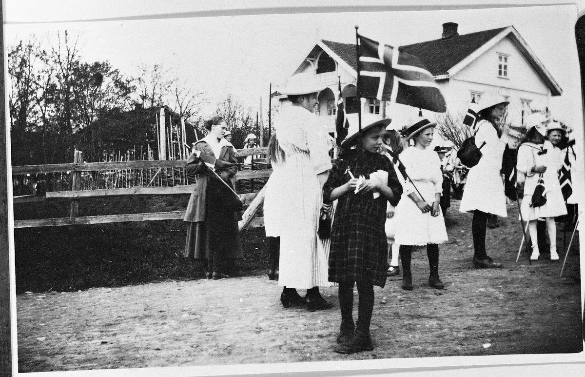 17.mai feiring på Hovsvangen 1918. Noen personer samlet øverst i vegen fra Hovsvangne ned mot riksvegen. Kommunelokalet til høyre, Hovsvangen skole bak til venstre.
