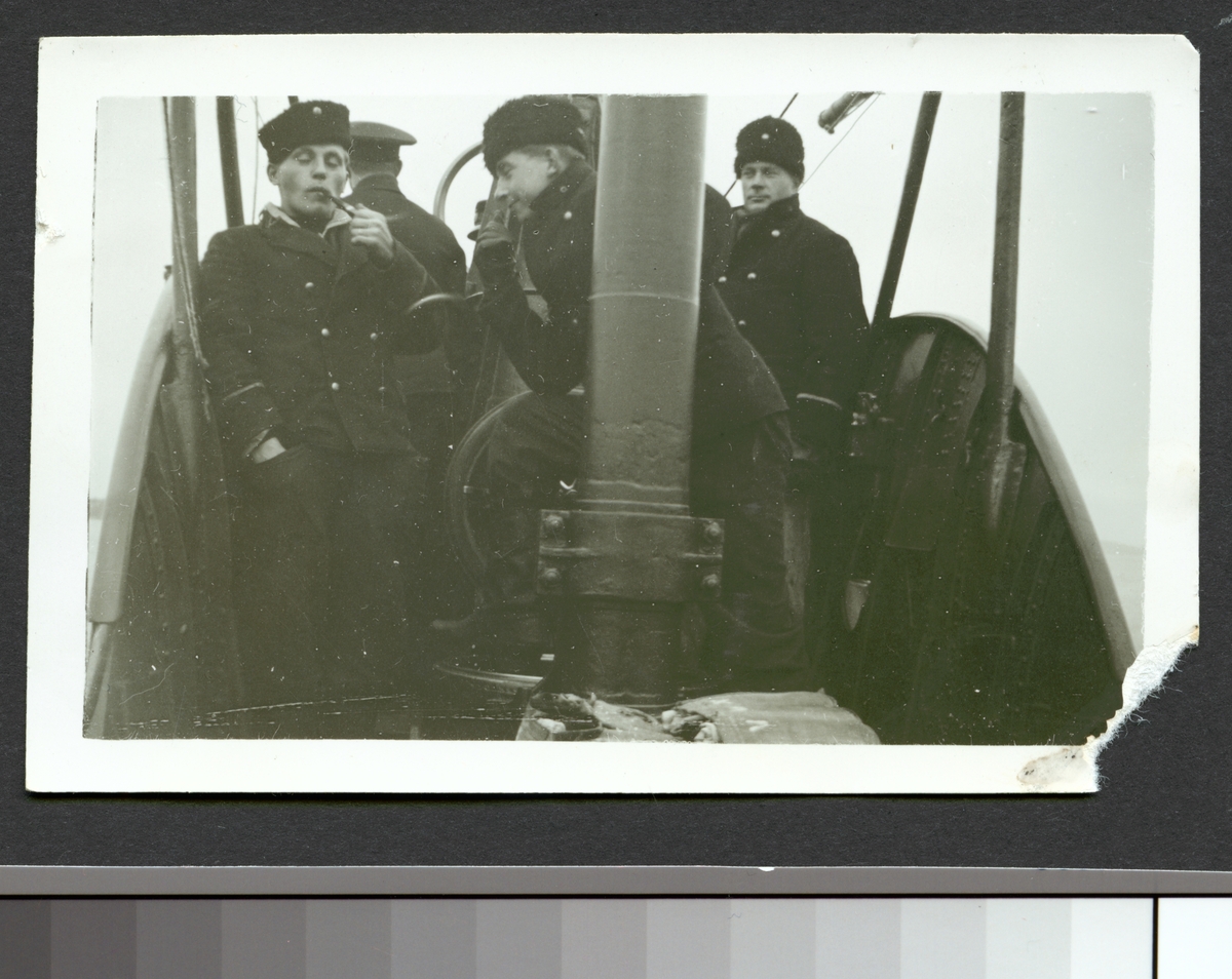 Bilden visar en grupp sjömän på däck av ubåten Valen till sjöss. Mannen till vänster verkar röka en pipa.