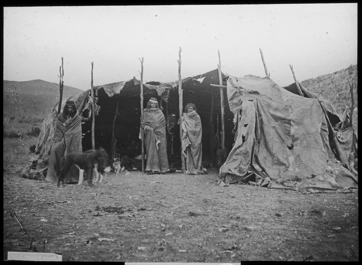 Bilden visar tre urinvånare från Patagonien som har tagit uppställning framför sin tält, en toldo, för fotografering.