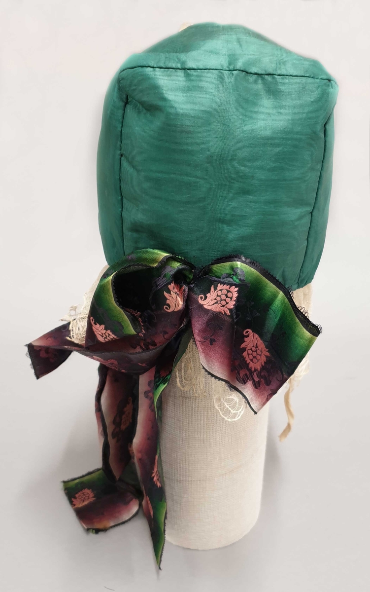Grønn strimmellue av silke, med silkesløyfe i grønt og burgunder.