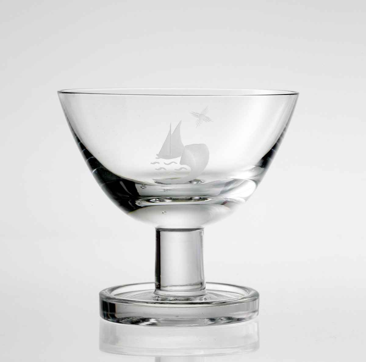 Design: Nils Landberg.
Madeiraglas. Tulpanformad kupa, med graverade segelbåtar på kupan. Lågt, konande ben med vulstkantad fot.