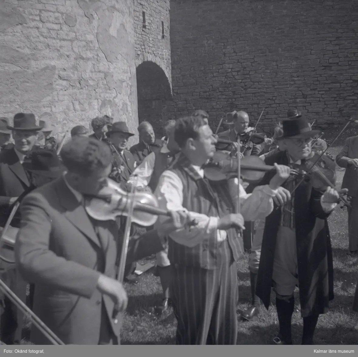 En orkester som spelar violin och folk som dansar i folkdräkter på Kalmar slott.