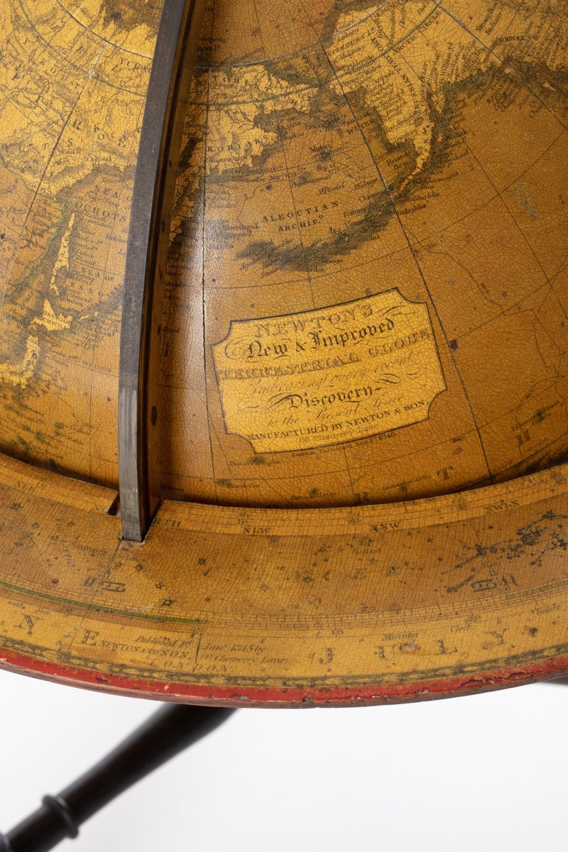Globus som er montert på et stativ med tre ben, dreid i tre, malt mørk brunt.