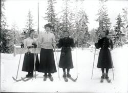 Fire unge kvinner på ski. To og to i nesten like drakter. Kv