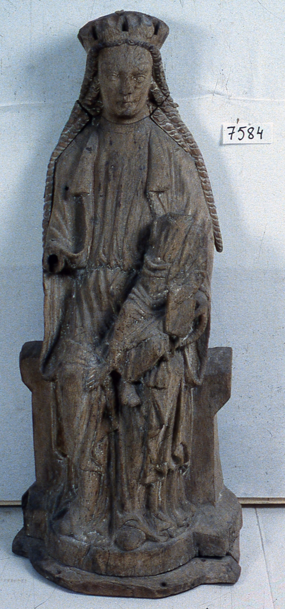 Skulptur föreställande Maria som sitter frontalt på en bänk med Kristusbarnet på vänster knä. Marias huvud har på 1400-talet bytts ut mot ett annat i samma material och med långt vågigt hår i furu. Pluggat hål i hjässan. Kronans blad avbrutna. Näsan skadad. Klädd i fotsid klänning som faller i mjuka veck över osynligt skärp. Över denna bär hon mantel med krage, draperad över armar och knän. Spetsiga skor sticker fram under klänningsfållen. Maria håller barnet med vänster hand, höger saknas. Barnet är klädd i tunika med draperad mantel. Håller bok i vänster hand. Höger arm saknas, huvudet borta. Tårna avslagna på vänster fot. All färg borta, spår av kredering. Halvrund fotplatta fästad på utspringande sockel. Urholkad baksida.  Se VFT 1983-84, Jan Svanberg: "Kornguden i Vånga och dess likar", sidan 101.